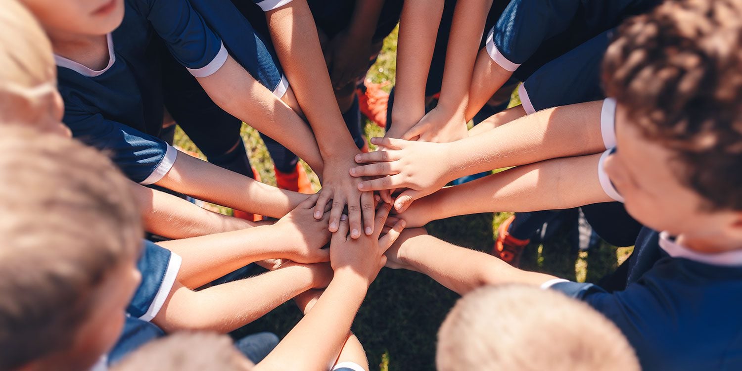 Children's hands stacked together in a huddle.